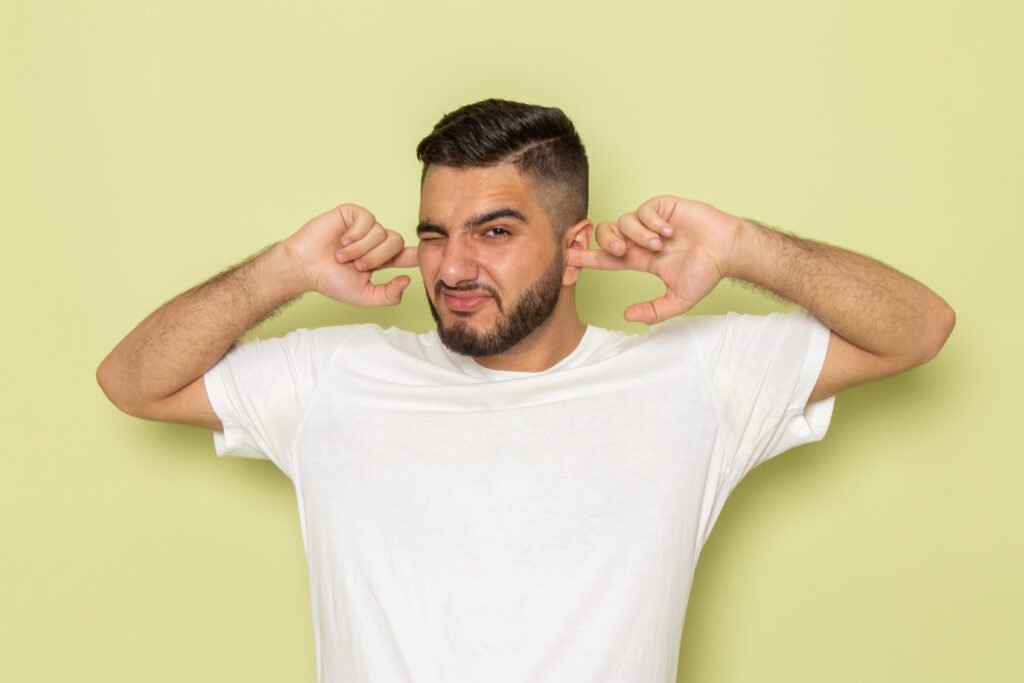 Uomo affetto da acufene tenta di coprirsi , invano ,le orecchie 