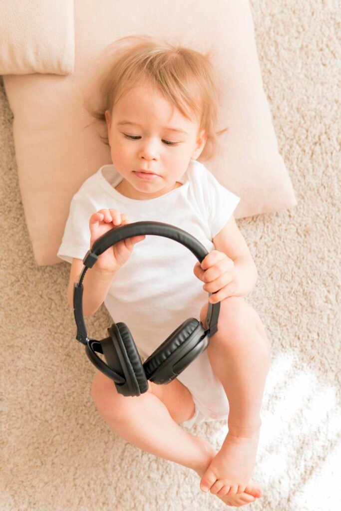 Bambino con in mano delle cuffie per riprodurre suoni bianchi per neonati che favoriscono sonno e relax