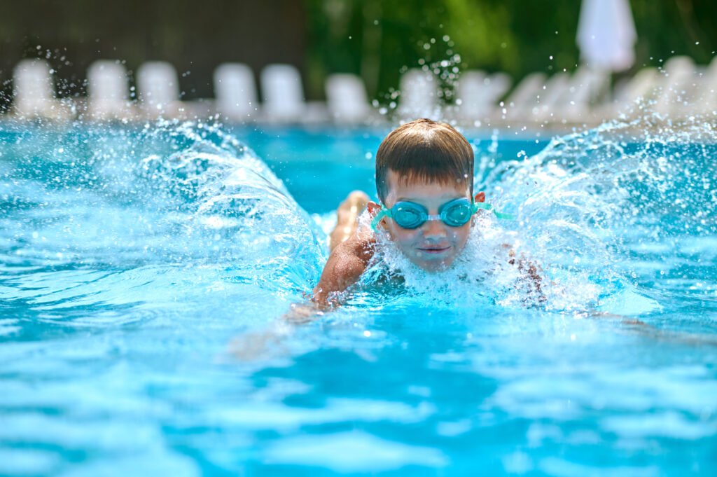 Ragazzo con gli occhialini nuota in piscina